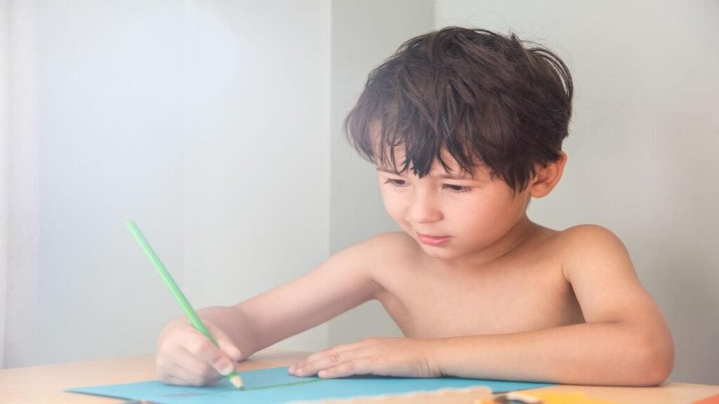 A young boy focused on drawing a straight green line on paper