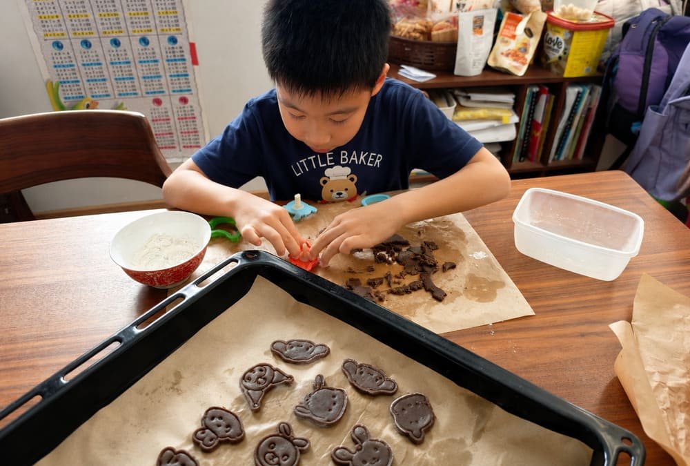 young boy baking cookies at home with cute cookie molds
