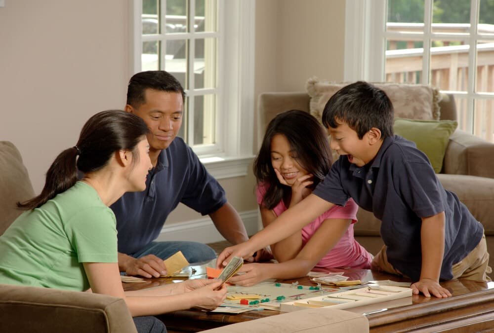 Family playing colourful drafting board games around a dining table
