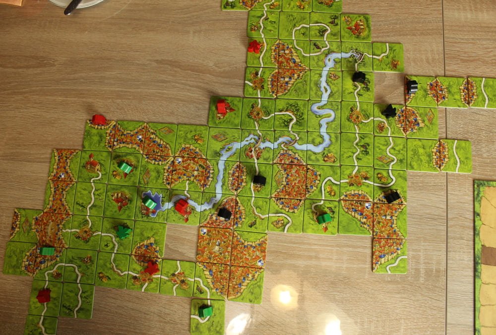 A large board game spread across a table mid-play, with pieces and cards in progress