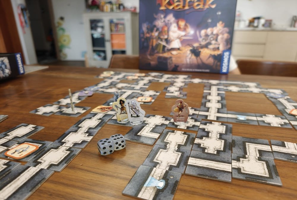 The board game Karak set up on a family dining table with dungeon tiles, character standees and dice mid-game