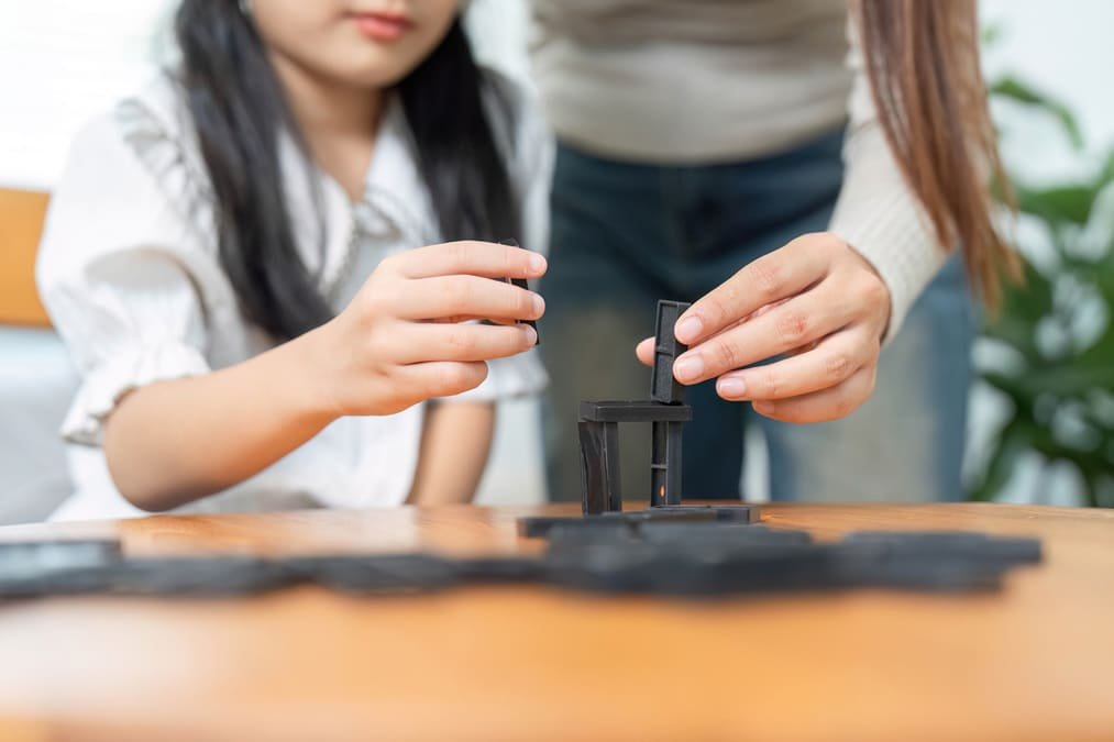 Close-up of a child's hands holding a game tile and working out where it connects on the board