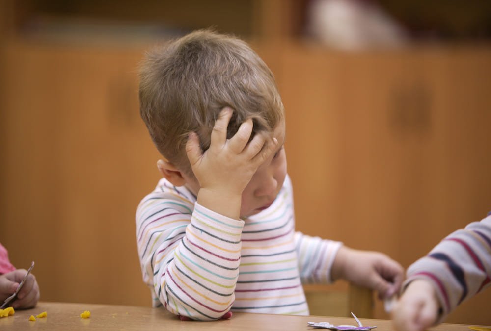 How to help your child lose a game? A child looking frustrated with his hand on his head from a board game.
