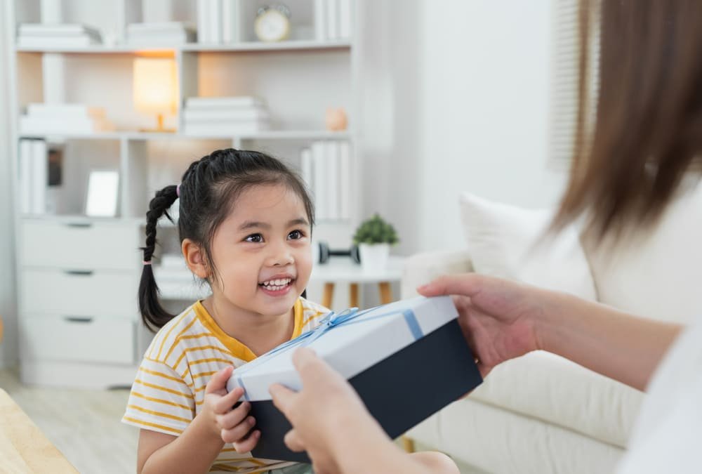 A child receiving a wrapped board game as a gift at home