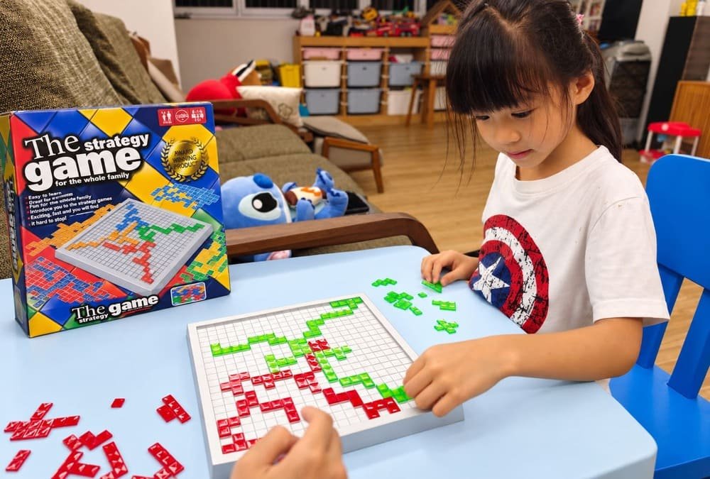 Child playing a strategy board game with colourful tiles to develop spatial reasoning and problem-solving skills.
